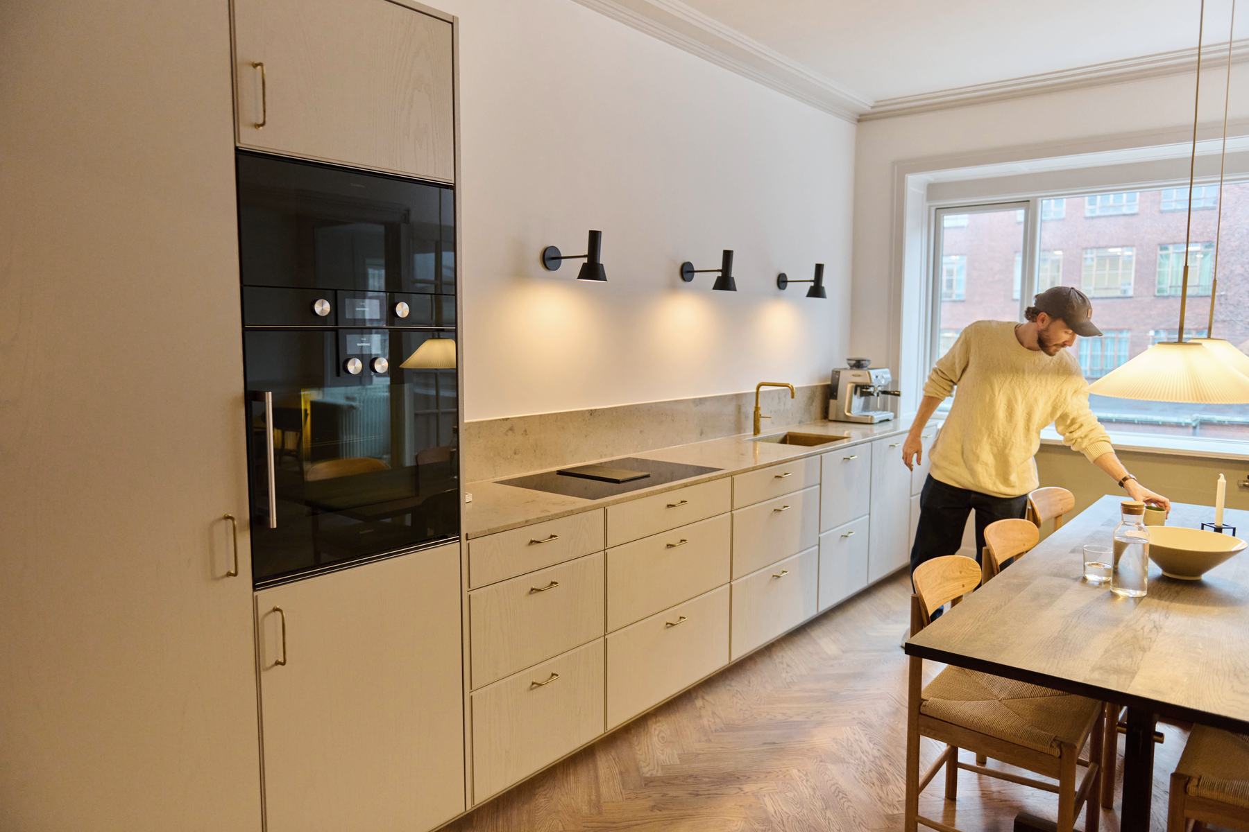 Langt køkken med højskabe, spisebord og sildebensparket